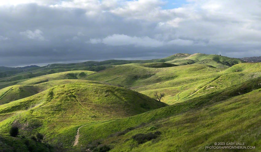 Filtered by clouds, the light of the setting sun highlights the green hills of Ahmanson Ranch (Upper Las Virgenes Canyon Open Space Preserve). Photography by Gary Valle'.