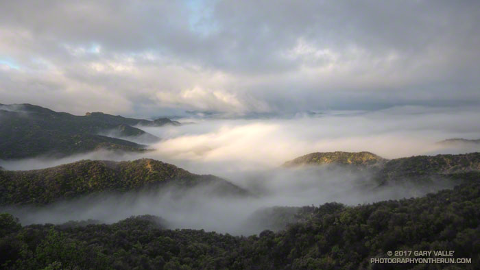 The first rays of sunlight illuminate the ridge tops, fog and clouds in the Santa Monica Mountains.