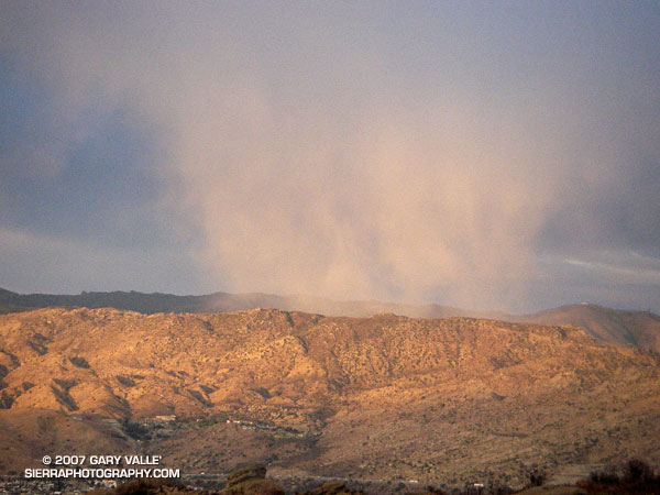 Low angle rays of the setting sun highlight a snow shower over the Rocky Peak