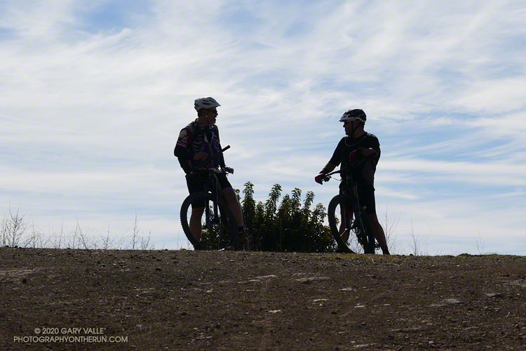 Mountain bikers silhouetted on the shoulder of the Etz Meloy fire road.