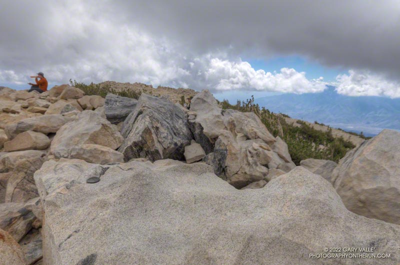 San Gorgonio's sibling summit with cloud-shrouded San Jacinto Peak in the distance. The data on the survey marker on the boulder in the foreground has been obliterated. September 24, 2022.